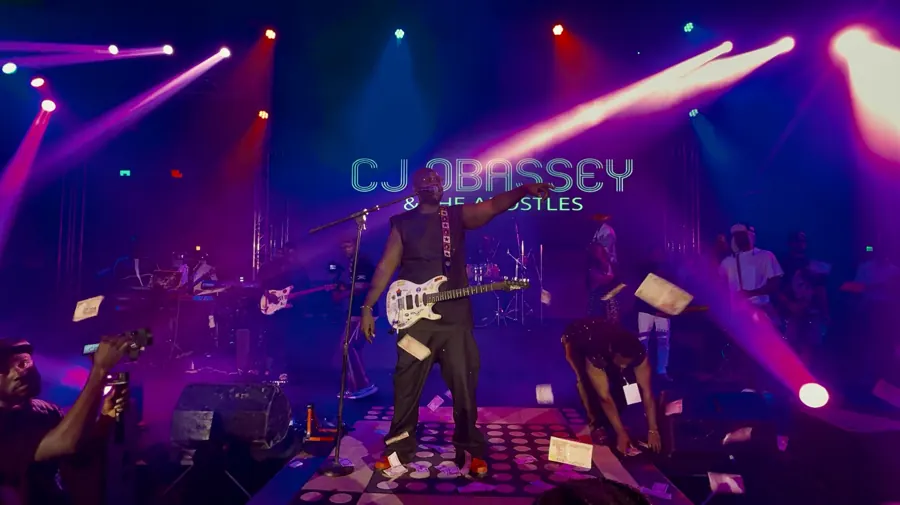 CJ Obassey and The Apostles on stage under purple and pink lights
