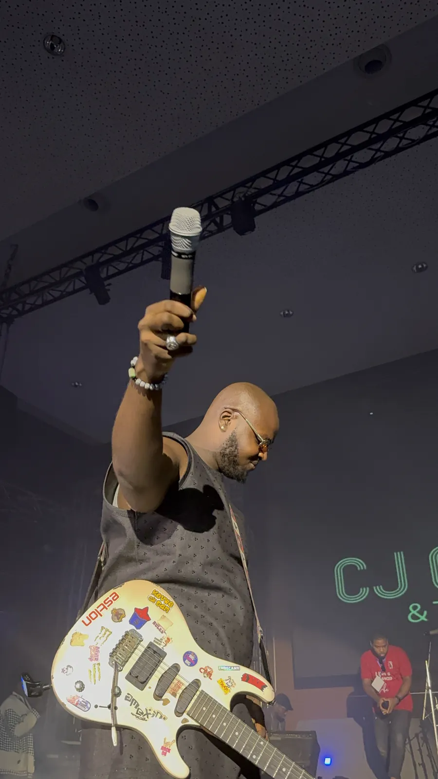 CJ Obassey raising a microphone above his head on stage