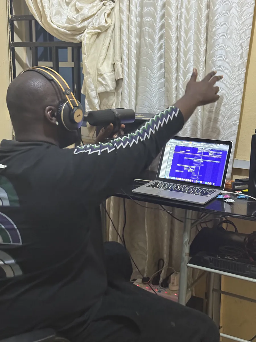 CJ Obassey in a studio session, headphones on, reaching towards the speakers