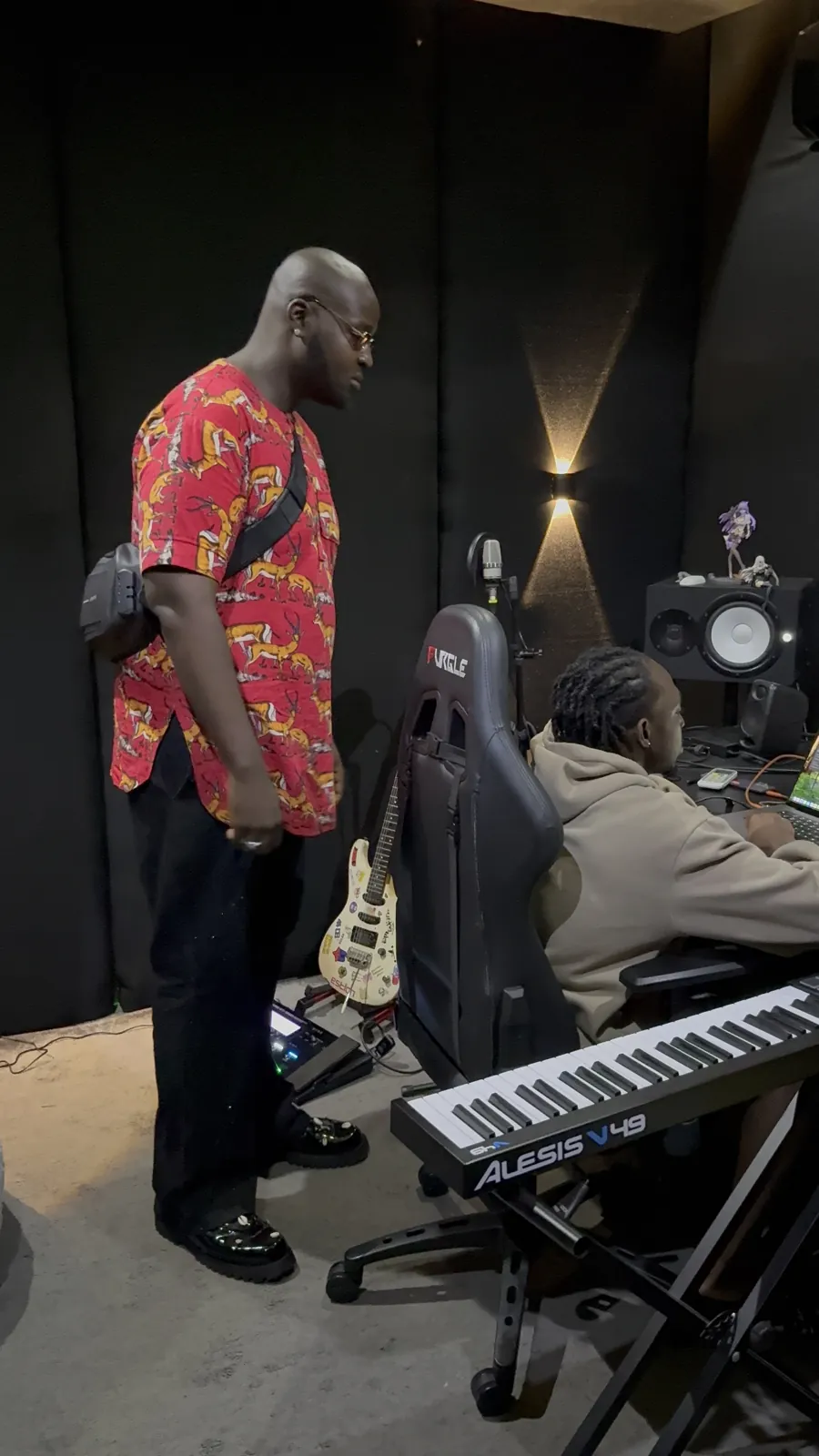 CJ Obassey standing over a producer at the desk during a studio session